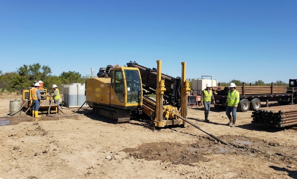 directional drilling rig with mud mixing system and crew on active Texas bore site